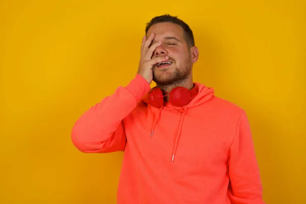 Young   man  with hand on face    against yellow  wall