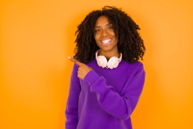 Güzel Afrikalı Amerikalı kadın sarı arka planı işaret ediyor..