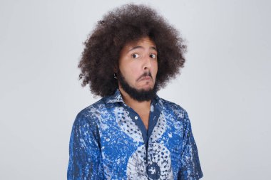 Züppe ifadeli güzel bir adam dudaklarını kıvırıyor ve kaşlarını kaldırıyor şüpheli ve şüpheci bir ifadeyle şüpheli ve şüpheci bir ifadeyle bakıyor. Gri arka planda kapalı duruyor..