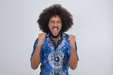 Güçlü, kararlı, sıradan giysiler içinde, kollarını kaldırarak, yumruklarını sıkarak, sevinç ve heyecanla haykıran genç bir erkeğin portresi. Zafer, başarı ve başarı kavramı.