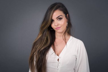 Stüdyoda, kıvırcık saçlı, sevimli bir gülümseme ile kameraya bakan güzel, genç, melez bir kadın modelin yakın çekimini yapın.