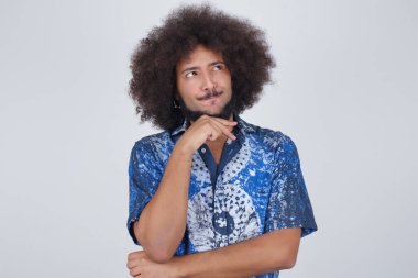 Hoş bir yüzü olan, günlük kıyafetler giyen, yan bakan, elini çenesinin altında tutan, hoş bir şeyler düşünen, gri arka planda poz veren hayalperest bir adam..