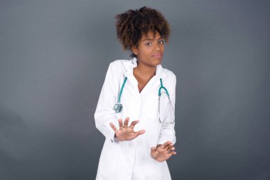 Güzel Afrikalı Amerikalı doktor kadın izole edilmiş arka planda korkmuş ve korkudan dehşete düşmüş, ve tiksindirici ifade iki elinle hareket etmeyi kes, orada kal. Panik konsepti.