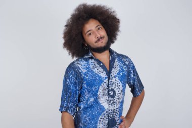 Neşeli adamın stüdyo çekimi elini kalçasında tutuyor, geniş bir gülümsemeyle, arkadaşlarının doğum gününde hazırladığı sürprizi bekliyor, gri arka planda izole edilmiş..