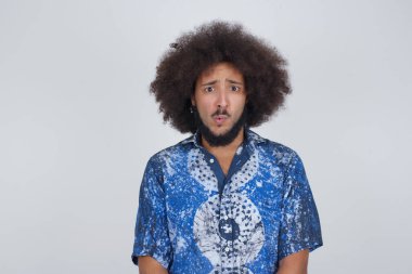 Gayri resmi giyinmiş esmer bir adam tiksinti, isteksizlik, hoşnutsuzluk ve umursamazlık ifadesi sergiliyor. Hoş görünümlü bir adam. Sinirli görünüyor. Bir şeyleri sindiriyor.