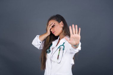 İnsanlar, vücut dili. Avrupalı genç doktor kadın avuçla gözlerini kapar ve dur hareketi yapar. Herkesten saklanmaya çalışır. Bana bakma, görmek istemiyorum, utanıyorum ya da korkuyorum..