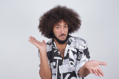 Yakışıklı adam ifadeden şüphe ediyor, şaşırıyor ve merak ediyor, belirsiz gelecek omuzlarını silkiyor, gri duvara karşı duruyor..