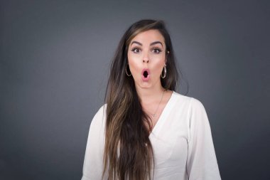 Çekici genç bir kadın ağzı açık, ağzı açık, ağzı açık bir şekilde şoke olmuş bir şekilde arkadaşının hikayesini dinlerken 