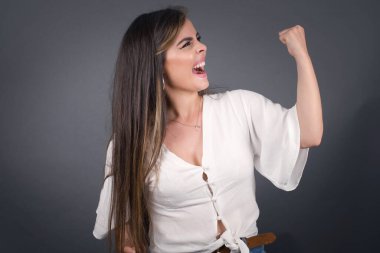 Çekici, beyaz bir kadın zaferi kutluyor yumruğuyla havaya yumruk atıyor ve arka planda fotokopi çekerek dişlek bir gülümseme yayıyor..