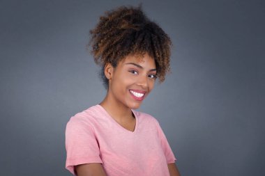 Utangaç, genç ve güzel Afrikalı Amerikalı kadın kameraya bakıp gülümsüyor.. 
