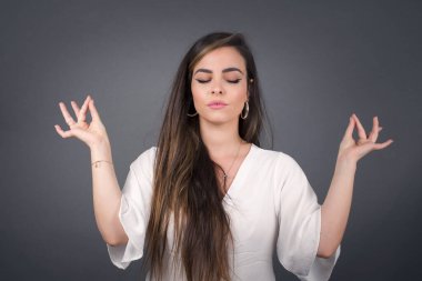 Meditasyon, din ve ruhani uygulamalar. Güzel genç bir kadın sabah uyandıktan sonra dışarıda yoga yapıyor, gözlerini kapalı tutuyor, Mudra jestinde parmaklarını tutuyor..