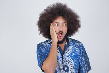 Şaşkınlık - adam heyecanla yüzüne bakıyor. Heyecandan yana bakan mutlu genç adam şaşırdı. Gri arka planda beyaz erkek model.