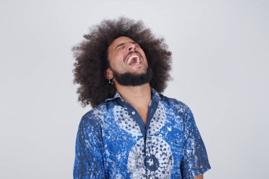 Neşeli Avrupalı bir adam iyi bir şakaya gülüyor ve eğleniyor ya da gri duvarda dikilerek günlük kıyafetler giyiyor. Mutlu adam içeride poz veriyor..