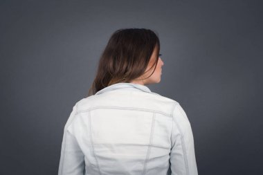 Gri duvara karşı dik duran bir kızın arka tarafı. Stüdyo Çekimi. 