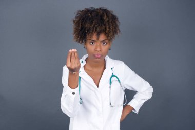 What the hell are you talking about. Shot of frustrated young African American  doctor woman gesturing with raised hand doing Italian gesture, frowning, being displeased and confused with dumb question.