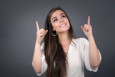 Başarılı, dost canlısı, parlak makyajlı, parlak saçlı bir kadının işaret parmağıyla işaret ederek boş bir fotokopi duvarında şok edici bir şey gösterdiği yatay bir görüntü..