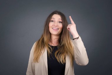 Tek parmakla göstererek, yukarı bakıp gülümseyen, gündelik kıyafetli çekici genç hipster kadının yakın plan portresi. Bir fikrim var, cevabı ya da çözümü biliyorum..