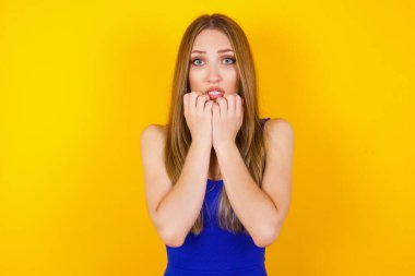 Endişe. Güzel, genç, beyaz bir kadının kavramsal görüntüsü. Ağzını elleriyle kaplıyor ve ayakta duruyor.