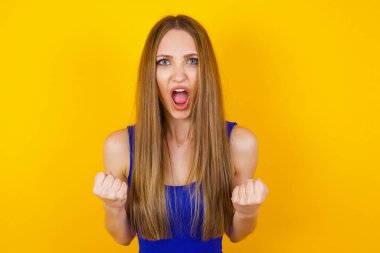 Güçlü, kararlı, sıradan kıyafetlerle, kollarını kaldırarak, yumruklarını sıkarak ve sevinçle golü haykırarak başarılı genç bir kadının portresi. Zafer, başarı ve başarı kavramı.