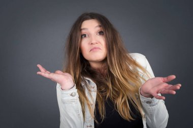 Güzel bir kadın ifadeden şüphe eder, şaşırır ve şaşırır, belirsiz bir gelecek omuzlarını silker, gri duvara karşı durur..