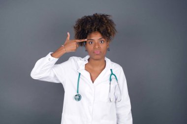 Mutsuz Afro-Afrikalı Amerikalı kadın doktor dudaklarını kıvırıyor ve intihar jesti yapıyor, her şeyden bıkmış, sinagogda elle çekim yapıyor, stüdyo arka planında izole edilmiş..