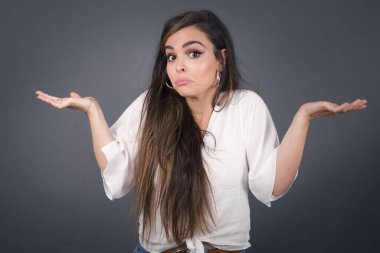 Kafası karışmış, kolları açık genç bir kadın omuzlarını silkip 