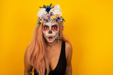 Cadılar bayramı makyajlı çekici genç bir kadın ağzı açık ve ağzı açık bir şekilde şaşkınlık içinde, arkadaşının hikayesini dinlerken 