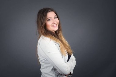 İçerde kollarını kavuşturmuş neşeli beyaz bir kadının görüntüsü. Kameraya bakıp gülümsüyor. Kendine güvenen kız..