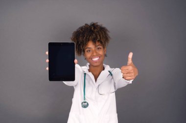 Gri stüdyoda steteskoplu Afrika kökenli Amerikalı kadın doktor.