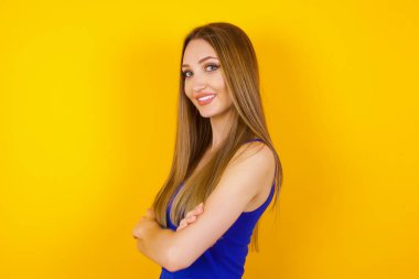 İçerde kollarını kavuşturmuş neşeli beyaz bir kadının görüntüsü. Kameraya bakıp gülümsüyor. Kendine güvenen kız..