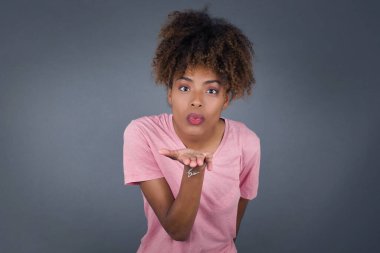 Siyah saçlı tatlı Afro-Amerikan kadın kameraya öpücük yolluyor.