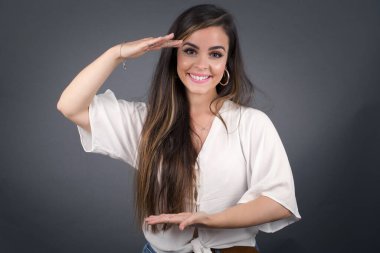 Sarışın Avrupalı bir kadın, izole edilmiş arka planda, elleri büyük ve büyük bir işaret, ölçü sembolü gösteriyor. Kameraya bakıp gülümsüyor. Ölçüm konsepti.