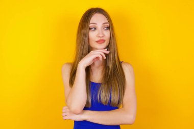 Yüzünde hoş bir ifade olan hayalperest bir kadın ellerini çenesinin altında tutuyor ve bir şeyler düşünüyor. 