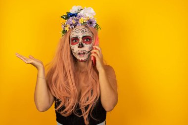 Telefonda cadılar bayramı makyajlı genç bir kadın izole bir arka planda konuşuyor. Yüzü asık, utangaç ve şaşırmış bir halde, sinirli ve hayal kırıklığına uğramış bir halde. Hata için korku ve üzüntü.