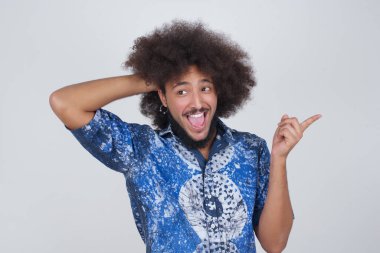 Şok olmuş yüz ifadesi olan genç bir adamın portresi, boş alanda inanılmaz bir şey gösteriyor, bir eli kafasında ve işaret parmağıyla işaret ediyor. OMG kavramı.