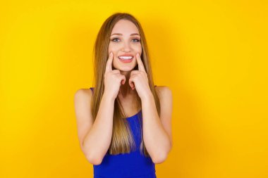 Güçlü, sağlıklı, beyaz dişlere sahip olma kavramı. Arka planda izole edilmiş, kusursuz beyaz dişlerini gösteren ışıltılı gülüşü olan mutlu genç kadının portresini yakından çek..