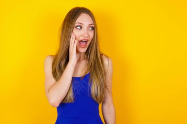 Heyecandan yana bakan mutlu genç bir kadın. Sarı arka planda beyaz kadın modeli.