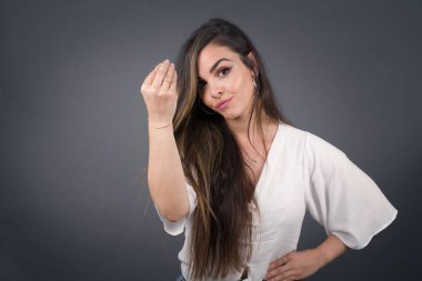 What the hell are you talking about. Shot of frustrated young European woman gesturing with raised hand doing Italian gesture, frowning, being displeased and confused with dumb question.
