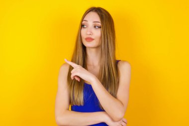 Kamerada poz veren güzel esmer bir kadın. Alengirli bir bakışla ve el kol hareketleriyle. Bayan tasarımcı, işaret parmağıyla harika bir ürün sunuyor. Hareket kavramı.