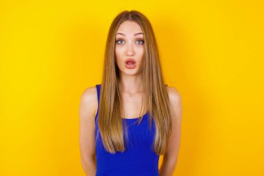 Çekici genç bir kadın ağzı açık, ağzı açık, ağzı açık bir şekilde şoke olmuş bir şekilde arkadaşının hikayesini dinlerken 