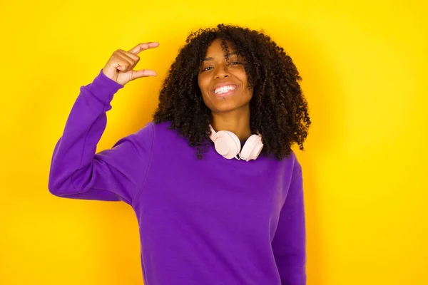 アフリカ系アメリカ人の女性は黄色の背景に指で小さなサイズを示しています 感情やジェスチャーの概念 — ストック写真