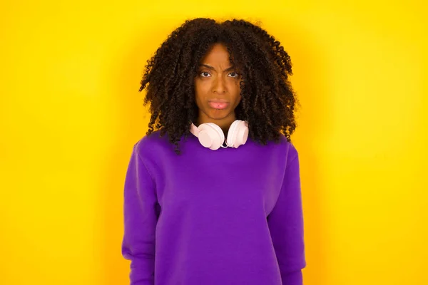 紫色の編まれたセーターを身に着けている若い美しいアフリカ系アメリカ人女性は黄色の背景に対して悲しいです — ストック写真