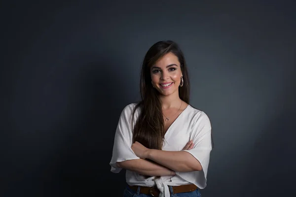 portrait of young smiling caucasian woman with long hair wearing casual blouse on a dark background.