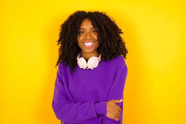 若い美しいアフリカ系アメリカ人女性は 紫色のニットセーターを着用し 黄色の背景に渡って腕を交差 — ストック写真