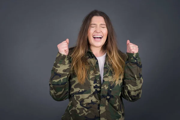 Caucasian brunette woman rejoicing her success and victory clenching her fists with joy. Lucky woman being happy to achieve her aim and goals. Positive emotions, feelings.