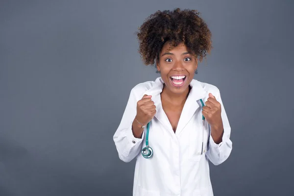 Caucasian young doctor woman rejoicing her success and victory clenching her fists with joy. Lucky woman being happy to achieve her aim and goals.