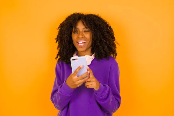 Mujer Afroamericana Guiño Sonrisa Mientras Sostiene Teléfono Inteligente Con Ambas — Foto de Stock
