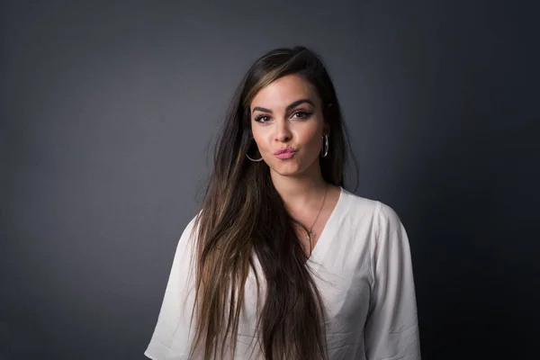 Attractive light haired female rounds lips, wears yellow turtleneck sweater, looks directly into camera, expresses her satisfaction, isolated over gray background. People, body language concept