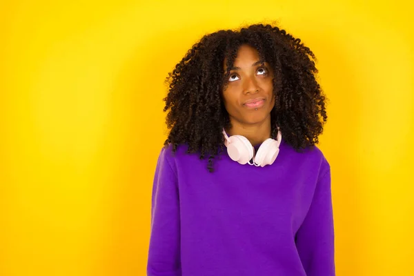 若い美しいアフリカ系アメリカ人女性は 紫色の編まれたセーターを着て黄色の背景に目を向ける — ストック写真