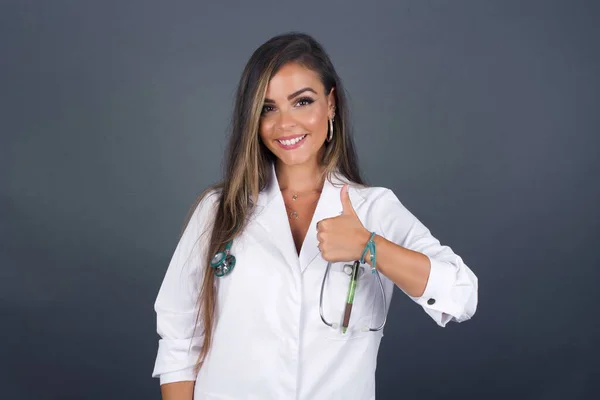 Good job! Portrait of a happy smiling  young successful doctor woman giving thumb up gesture standing outdoors. Positive human emotion facial expression body language. Funny girl